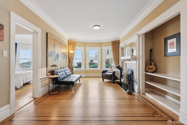 sitting room featuring baseboards, a fireplace, wood finished floors, and crown molding