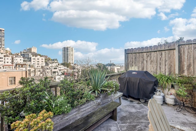 view of patio / terrace with a view of city, a grill, and fence