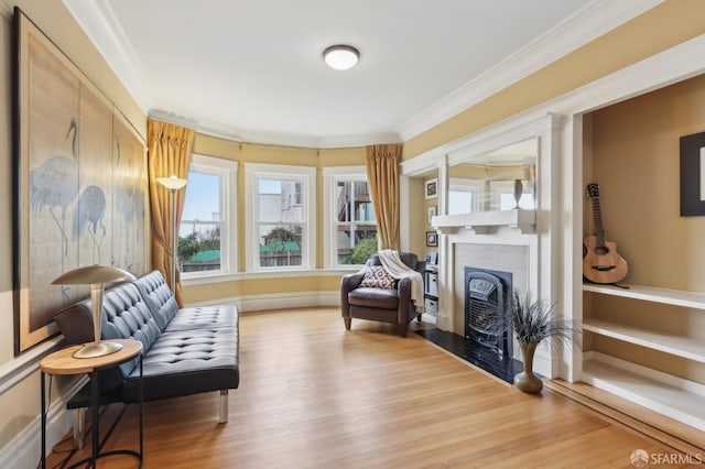 sitting room featuring ornamental molding, a fireplace, baseboards, and wood finished floors