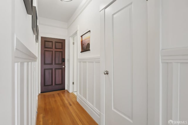 hall featuring light wood-style floors and a decorative wall