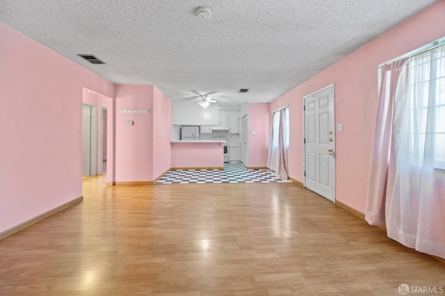 unfurnished living room with a textured ceiling, light wood-type flooring, and ceiling fan