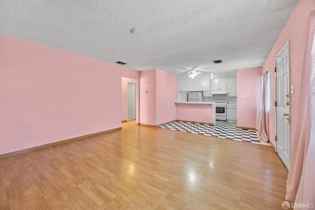 unfurnished living room with ceiling fan, a textured ceiling, and light wood-type flooring