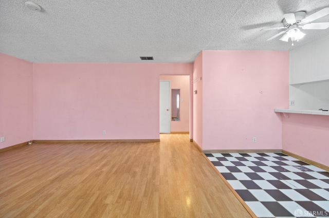 unfurnished room featuring ceiling fan, light hardwood / wood-style floors, and a textured ceiling