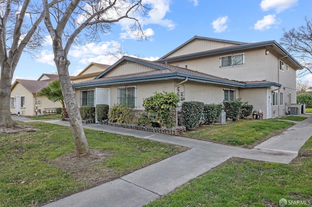 view of property with central air condition unit and a front yard