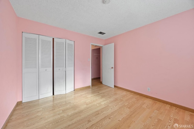 unfurnished bedroom with light wood-type flooring, a textured ceiling, and a closet