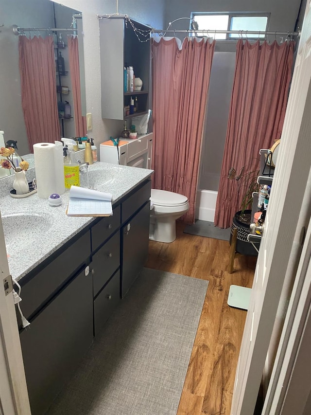 bathroom featuring toilet, shower / bath combo, wood finished floors, and vanity