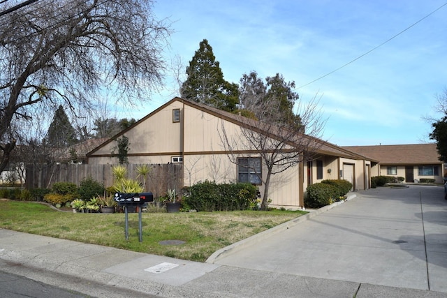 view of front of home featuring driveway, an attached garage, fence, and a front yard