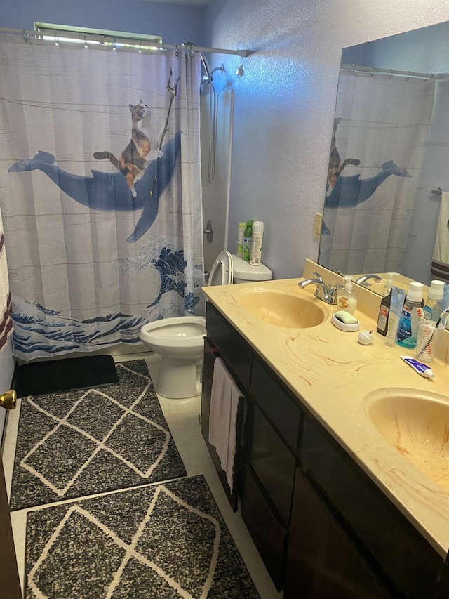 bathroom with double vanity, a shower with shower curtain, a sink, and toilet