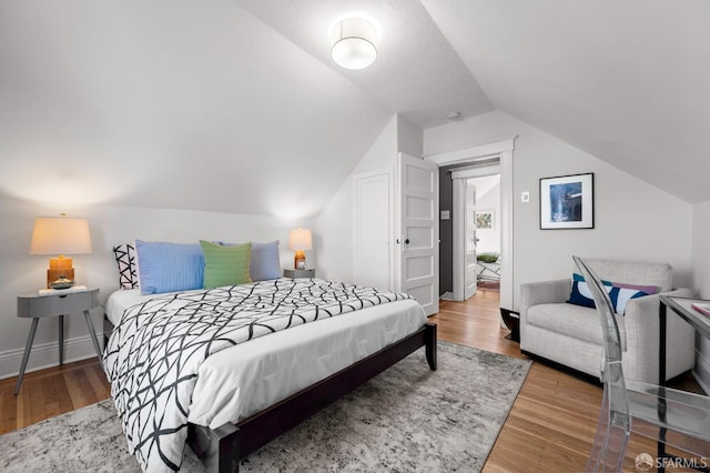 bedroom featuring baseboards, vaulted ceiling, and wood finished floors