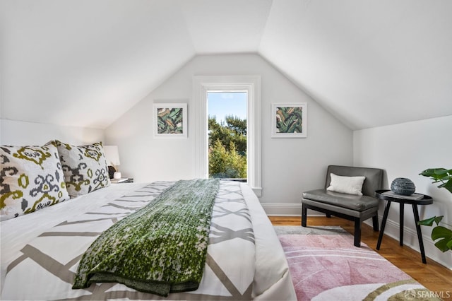 bedroom featuring baseboards, vaulted ceiling, and wood finished floors