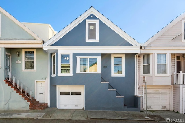 view of front of house featuring a garage, stairway, and stucco siding