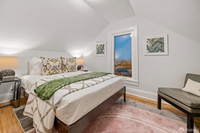 bedroom featuring baseboards, vaulted ceiling, and wood finished floors