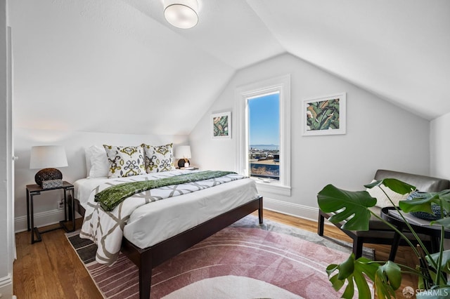 bedroom with baseboards, vaulted ceiling, and wood finished floors