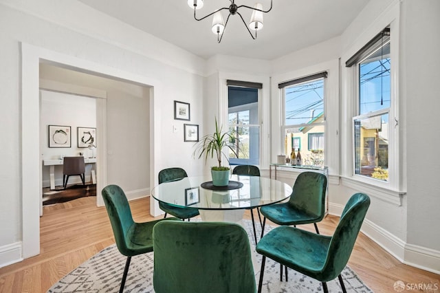 dining room featuring light wood-type flooring, an inviting chandelier, and baseboards