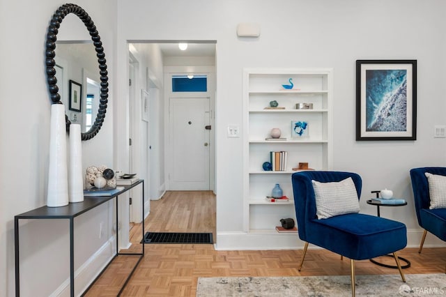 sitting room featuring built in features, visible vents, baseboards, and parquet flooring