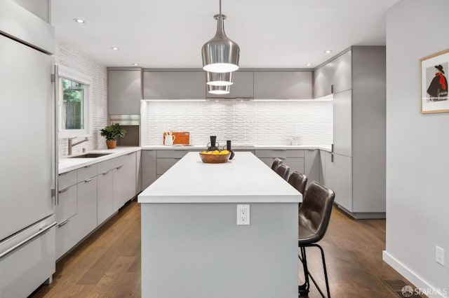 kitchen with a center island, gray cabinets, high end white fridge, a sink, and a kitchen breakfast bar