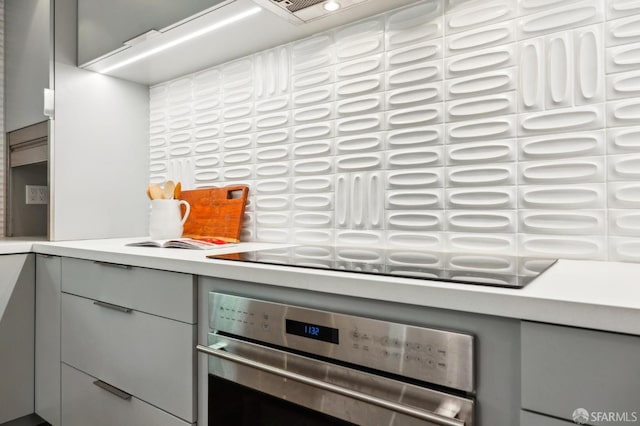 kitchen with black electric stovetop, gray cabinets, light countertops, and oven