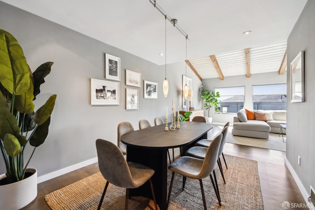 dining room with lofted ceiling with beams, wood finished floors, and baseboards