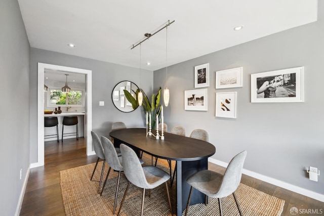 dining space with recessed lighting, rail lighting, dark wood finished floors, and baseboards