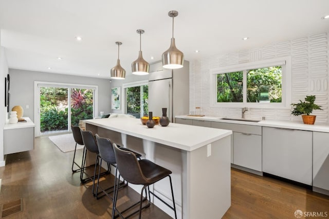 kitchen featuring a breakfast bar, a sink, a kitchen island, visible vents, and light countertops