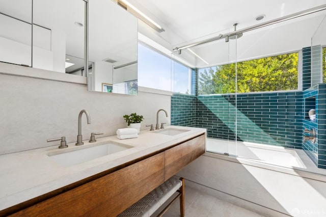 full bath with a healthy amount of sunlight, double vanity, and a sink