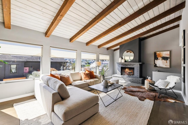 living area featuring a brick fireplace, baseboards, beam ceiling, and wood finished floors