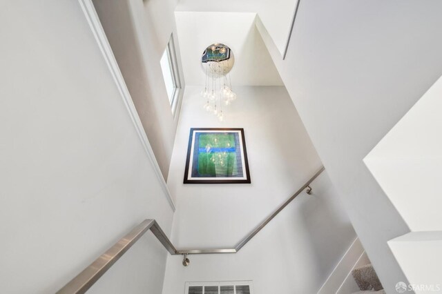 staircase featuring an inviting chandelier and visible vents