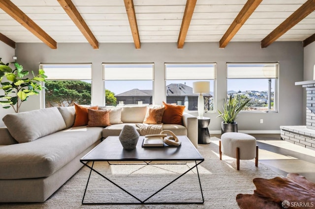 living area with beam ceiling, a fireplace, baseboards, and wood finished floors