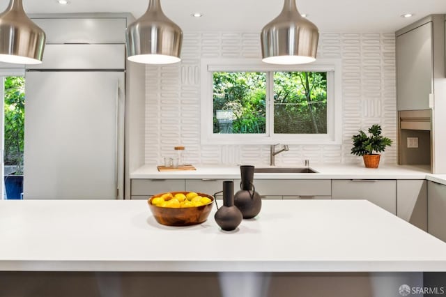 kitchen featuring tasteful backsplash, light countertops, gray cabinetry, a sink, and modern cabinets