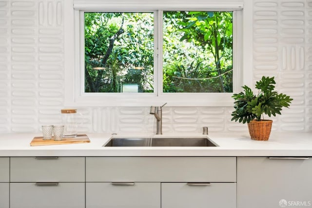 kitchen featuring white cabinets, light countertops, and a sink