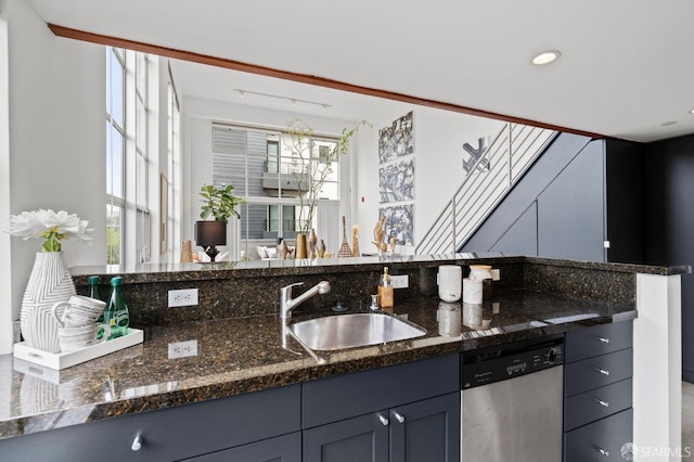 kitchen with sink, stainless steel dishwasher, and dark stone counters