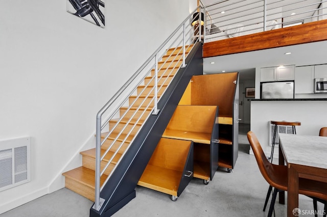 stairs featuring a towering ceiling and concrete floors