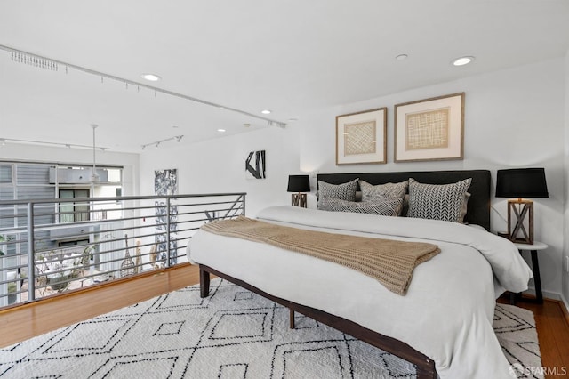 bedroom featuring hardwood / wood-style floors and track lighting