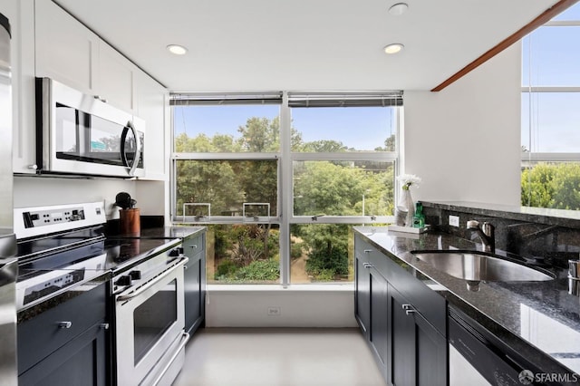 kitchen featuring white cabinetry, stainless steel appliances, sink, and dark stone counters