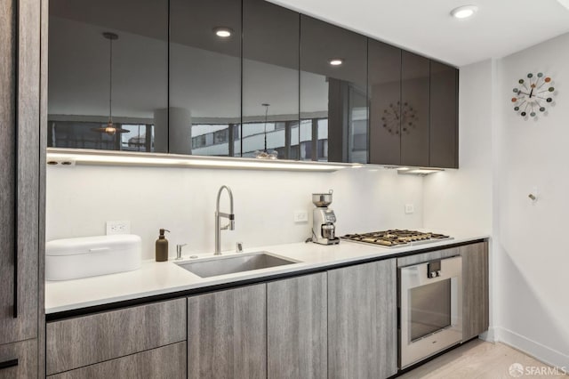 338 Main St Unit 6E, San Francisco, CA 94105 - kitchen with a sink, wall oven, stainless steel gas stovetop, modern cabinets, and light wood-style floors
