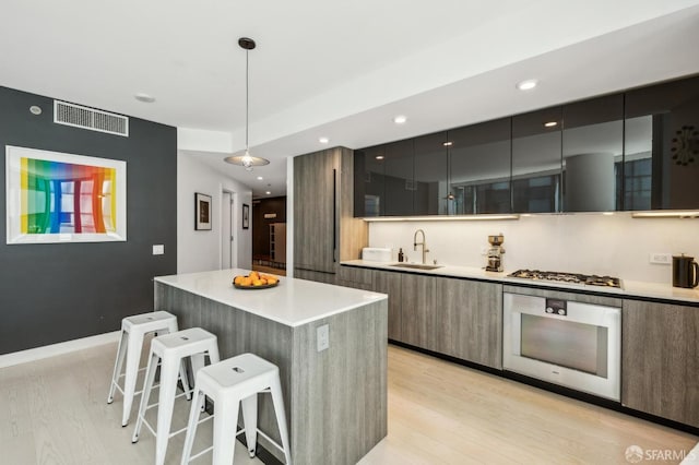 338 Main St Unit 6E, San Francisco, CA 94105 - kitchen with modern cabinets, oven, a sink, light wood-style floors, and recessed lighting