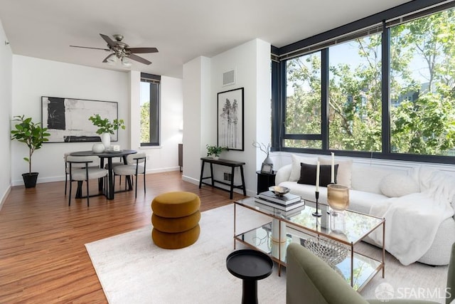 living room with ceiling fan, wood finished floors, and baseboards