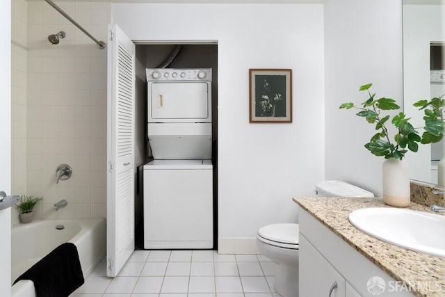 bathroom featuring stacked washer and clothes dryer, tile patterned flooring, tub / shower combination, vanity, and toilet