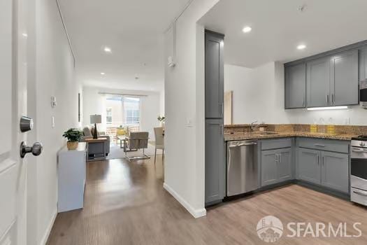 kitchen featuring gray cabinets, dishwasher, dark stone countertops, and light hardwood / wood-style floors