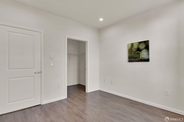 unfurnished bedroom with wood-type flooring and a walk in closet