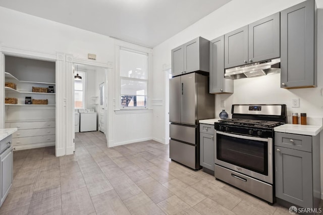 kitchen with gray cabinets, stainless steel appliances, and washing machine and clothes dryer