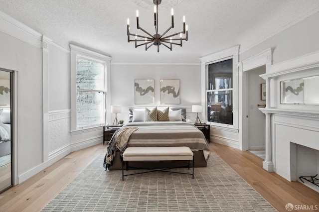 bedroom with multiple windows, a textured ceiling, and light wood-type flooring