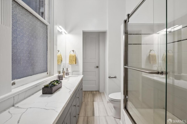 bathroom featuring toilet, walk in shower, and vanity