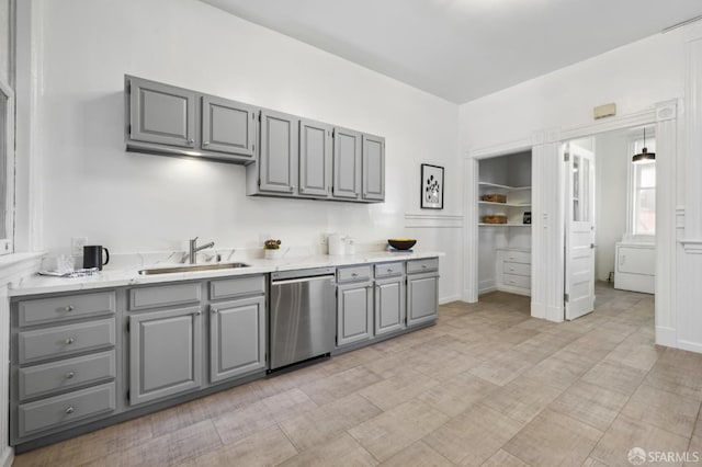 kitchen with gray cabinetry, stainless steel dishwasher, washer / clothes dryer, and sink