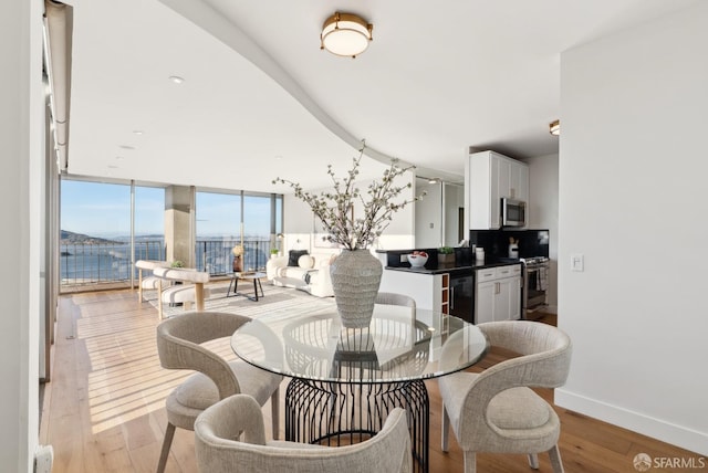 dining room featuring light wood finished floors, wine cooler, and baseboards