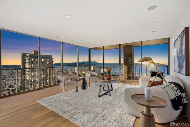 living area with expansive windows, a mountain view, and wood finished floors