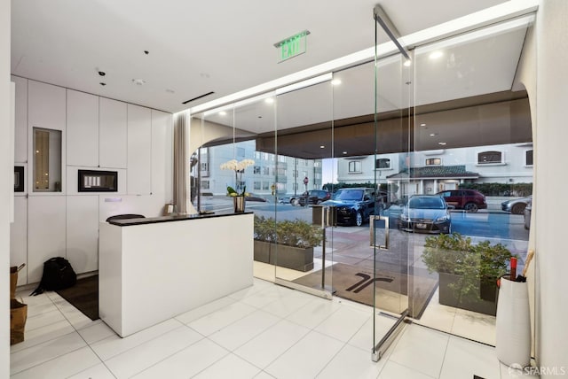 interior space featuring tile patterned flooring, white cabinetry, expansive windows, and modern cabinets