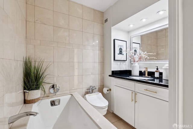 bathroom with toilet, tile patterned flooring, a washtub, vanity, and tile walls