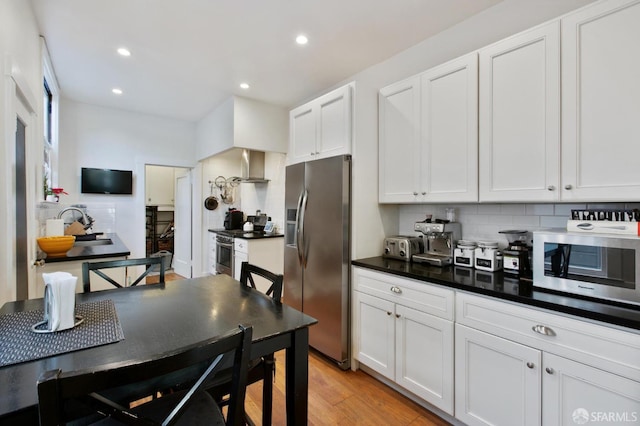 kitchen featuring stainless steel appliances, light hardwood / wood-style floors, white cabinetry, and tasteful backsplash