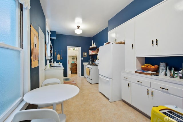 kitchen with white appliances, sink, and white cabinetry